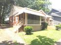 Side view of a charming brick home featuring a screened porch, landscaped yard, and a cozy, welcoming appeal at 1712 Clifton Se Way, Atlanta, GA 30316