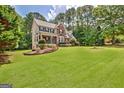 Two-story home with a brick and light yellow facade, large lawn, and mature trees at 145 Driftwood Trl, Fayetteville, GA 30215
