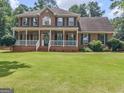 Charming brick home featuring a classic white porch, green shutters, and a well-maintained lawn at 416 River Forest Dr, Mcdonough, GA 30252