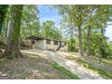 Charming single-story home featuring a blue front door, painted brick, a driveway and mature trees at 3833 Bakers Ferry Sw Rd, Atlanta, GA 30331