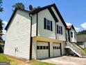 Side view of the house showing the 2-car garage, siding, dark shutters, and well-maintained yard at 5445 Maltdie, Sugar Hill, GA 30518