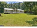 Ranch-style home featuring a cozy front porch and a spacious, lush green yard at 147 Pine St, Covington, GA 30014