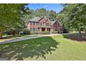 Two-story brick home nestled among lush green trees and manicured landscaping at 100 Old Plantation Way, Fayetteville, GA 30214