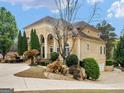 Side view of a traditional residence with a portico, manicured shrubs, and a side-entry garage at 5297 Heron Bay Blvd, Locust Grove, GA 30248