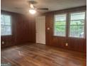 Living room featuring wood paneling, multiple windows, ceiling fan, and light-colored door at 8833 Thomas Rd, Jonesboro, GA 30238
