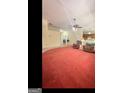 Spacious living room with red carpeting, ceiling fan, and a glimpse into the entry way at 180 Tabor Forest Dr, Oxford, GA 30054