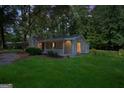 Charming home with a covered front porch, siding, a brick chimney, and illuminated porch lights at dusk at 6770 Burkhead Dr, Union City, GA 30291