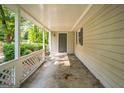 Covered front porch featuring white lattice railing, gray siding, and a gray front door with leafy foliage nearby at 6770 Burkhead Dr, Union City, GA 30291