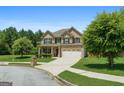 Attractive two-story brick home showcasing lush landscaping, a two-car garage, and a covered front porch at 4770 Macy Way, Ellenwood, GA 30294
