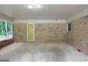 Spacious carport area featuring brick walls, concrete flooring and a yellow exterior door at 4852 Pine Shadows, Stone Mountain, GA 30088