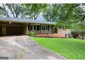 Well-maintained home showcasing a brick facade, covered carport, and lovely landscaping at 4852 Pine Shadows, Stone Mountain, GA 30088