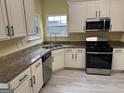 Modern kitchen featuring stainless steel appliances, white cabinets, and laminate flooring at 4199 Elderberry Nw Dr, Acworth, GA 30101