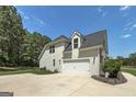 Spacious garage with an expansive driveway and a well-maintained lawn surrounded by lush trees at 433 Wilson Dr, Mcdonough, GA 30252