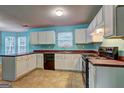 Well-lit kitchen features white cabinets, dark countertops, tile flooring, and modern appliances for easy living at 1067 Misty Meadows Pt, Hampton, GA 30228