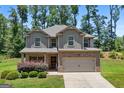 Charming two-story home with a brick-accented front and attached two-car garage, set against a backdrop of lush greenery at 470 Louise Way, Locust Grove, GA 30248