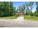 Two-story home with a brick-accented two-car garage, green lawn and mature trees lining the property's edge at 470 Louise Way, Locust Grove, GA 30248