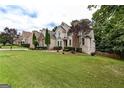Brick home featuring manicured lawn, mature trees and decorative stone accents at 1360 Mount Mckinley Dr, Grayson, GA 30017