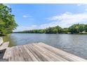 A lakeside view from a weathered wooden dock, showing tranquil waters and the opposite tree-lined shore at 660 Milton Dr, Mcdonough, GA 30252