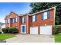 Red brick home featuring a well-manicured lawn, blue shutters, and a two-car garage at 3796 Wolverton Cir, Lithonia, GA 30038