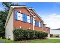 Side view of a red brick home with blue shutters, a manicured lawn, and mature shrubbery at 3796 Wolverton Cir, Lithonia, GA 30038