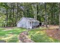 Backyard view of a quaint house featuring light blue shutters and a peaceful wooded setting at 85 London Ln, Sharpsburg, GA 30277