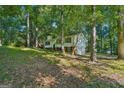 Home exterior surrounded by mature shade trees on a well-maintained lawn and dark shutters at 4496 Housworth Dr, Lithonia, GA 30038