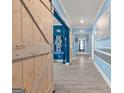 Hallway features light gray plank flooring, light blue walls, and rustic barn-style doors at 400 Plainfield St, Fayetteville, GA 30215