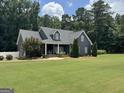 Inviting two-story home with a rocking chair front porch and large, well-maintained front lawn at 180 Cooper Rd, Social Circle, GA 30025