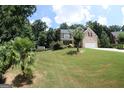 Spacious front yard with mature trees and landscaping leading to a charming brick two-story home at 305 Matthew Cir, Stockbridge, GA 30252