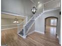 Light-filled foyer with hardwood floors, white staircase, elegant chandeliers, and views of the living spaces at 7910 Tintern Trce, Duluth, GA 30097