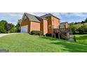 Two-story brick home featuring an attached garage and a spacious grassy yard at 165 Mcelwaney Way, Fayetteville, GA 30215
