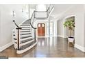 Elegant foyer featuring a curved staircase with dark wood accents, bright light, and beautiful hardwood floors at 4203 Harrogate Nw Dr, Atlanta, GA 30327