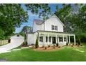 Charming white farmhouse with black shutters, a welcoming front porch, and a detached garage at 61 Main St, Moreland, GA 30259