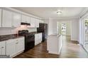 Modern kitchen with white cabinets, black appliances, and an island sink at 3260 Russell St, Hapeville, GA 30354