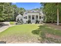 Beautiful white home with a classic columned porch, manicured lawn, and lush, mature trees at 275 Sidney Ln, Fayetteville, GA 30215