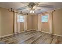 Cozy bedroom featuring wood-look floors, two windows with curtains, and a ceiling fan with lights at 315 Charlotte Blvd, Stockbridge, GA 30281