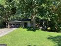 A single story home with a well-kept lawn and established trees offering shade at 215 Lakeland Ct, Roswell, GA 30076