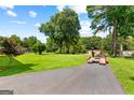 Large grassy yard with driveway and lush trees enhancing the property's curb appeal at 80 David Rd, Hampton, GA 30228