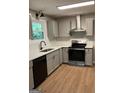 Modern kitchen with light gray cabinets, black appliances, and stainless steel range hood at 1608 Bogota Way, Jonesboro, GA 30236