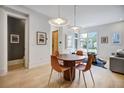 Open dining area with stylish lighting fixtures and wood floors flowing into the living area with comfortable seating at 10871 Serenbe Ln, Chattahoochee Hills, GA 30268