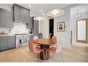 Modern kitchen with gray cabinets, stainless steel appliances, quartz countertops, and adjacent dining area with pink chairs at 10871 Serenbe Ln, Chattahoochee Hills, GA 30268