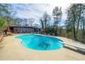 Large, in-ground pool with a diving board and sunbathing area, surrounded by trees and lush landscaping at 3679 Herschel Rd, College Park, GA 30337