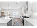 Bright modern kitchen featuring white cabinets, stainless steel appliances, quartz countertops, and pendant lighting at 3317 Stillwood Ln, Hapeville, GA 30354
