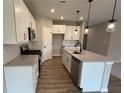 Bright kitchen features stainless appliances, stone countertops and a central island with a sink and stylish pendant lighting at 128 Laurel Farms Ln, Dallas, GA 30157