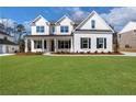 Charming two-story home with white brick, a covered porch, and a lush green lawn at 6670 Benchwood Path, Cumming, GA 30028