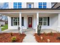 Close-up of a front porch featuring a red door, white columns, and manicured landscaping at 6670 Benchwood Path, Cumming, GA 30028