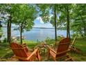 Stunning lake view with Adirondack chairs around a fire pit and mature trees at 7 Yachting Way, Acworth, GA 30102