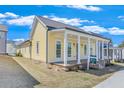 Attractive yellow home with a columned front porch, showcasing a pristine lawn and well-kept landscaping at 929 Hilltop Park Ct, Dacula, GA 30019