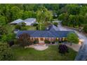 Aerial view of a brick home with a large lawn, mature trees, and a driveway leading to a garage at 3700 Tom Brewer Rd, Loganville, GA 30052