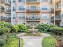 A courtyard garden features a stone fountain, manicured landscaping, and several apartment balconies at 230 E Ponce De Leon Ave # 322, Decatur, GA 30030